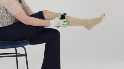 The woman moves the STEVE+ easyON upwards so that the compression stocking unrolls around the leg.