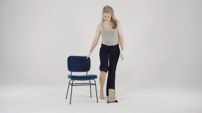 Woman grabs chair for balance in order to put on her stocking with stockingaid STEVE+ easyON.