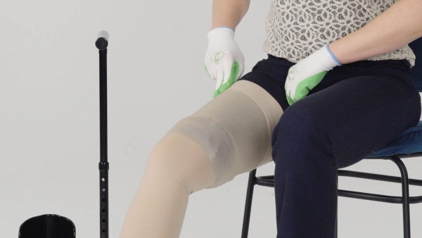 Woman wraps the edge of the groin stocking around the leg.